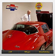 Biden está ao lado de um carro antigo vermelho em uma garagem.