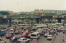 The east square of Guangzhou railway station in 1991. Traditional characters are prevalent in various brand logos, including
Jian Li Bao ; 'Jianlibao Group',
Piao Rou ; 'Rejoice', and
Yan Dong Mo Jia Le ; 'Guangdong Macro'. Only
Hai Fei Si ; 'Head & Shoulders' is using simplified characters in their wordmark. Guangzhou 1991.jpg