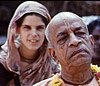 A young Western woman dressed in sari following an elderly Indian swami