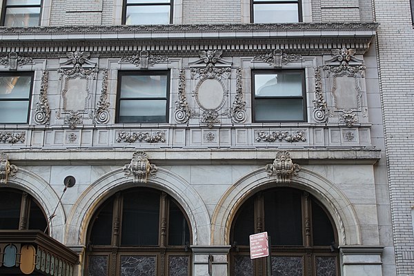 Detail of the mezzanine (bottom) and the second-story windows (top). The upper portion of each arch contains a tripartite iron frame. The second-story