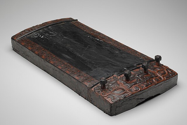 An ancient se board with four string posts, dated to the 5th–3rd centuries BC. Made of wood painted in black and red lacquer, and carved with decorati