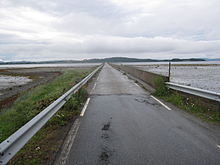 Foto einer engen Straße, die durch ein Gewässer führt