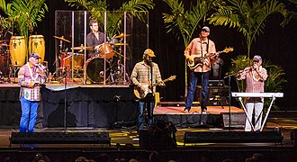 Mike Love (far left) and Bruce Johnston (far right) performing as the Beach Boys in 2014, with occasional guest-performer John Stamos on drums (back) The Beach Boys by Peter Chiapperino (cropped).jpg