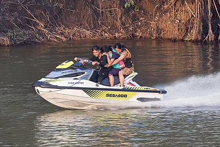 Three teenagers on a jetski running at full speed on the Mekong