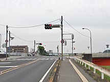 足利市・田中橋北交差点 （起点、2015年6月） ↑（東）方向が県道8号、→（南・田中橋）↓（西）が国道293号、←（北）が市道（至足利駅南口）である。