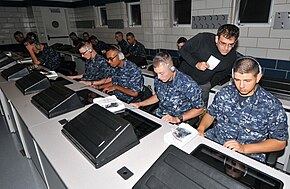 Dr. Talib Hussain, senior scientist at BBN Technologies, looks over the shoulder of a recruit during a training session on the Virtual Environments for Ship and Shore Experiential Learning system at Recruit Training Command. US Navy 100916-N-8848T-351 Dr. Talib Hussain, senior scientist at BBN Technologies, looks over the shoulder of a recruit during a training session.jpg