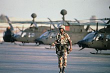 A sentry patrols along a line-up of OH-58 Kiowa helicopters United States Forces in the Gulf War 1991 GLF980.jpg