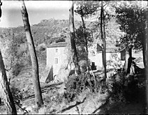 Vista d'una masia a través d'uns arbres