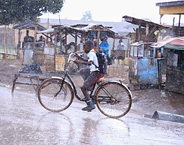 A boy riding a bicycle through the rain Photo by Joshua Mirondo
