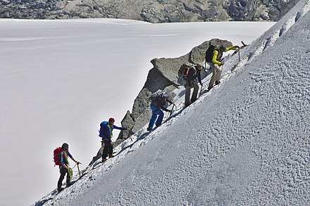 A rope team of five alpinists climbs the eastern slope of the Aiguille du Midi, Mont Blanc massif, France.