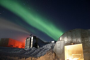 Vue de la station américaine Amundsen-Scott au pôle Sud, éclairée par la pleine lune, durant la longue nuit polaire. La nouvelle station est visible tout à gauche, la centrale électrique au centre et l'ancien atelier de mécanique en bas à droite. Durant la nuit polaire, seule la lumière rouge est utilisée pour limiter la pollution lumineuse et ne pas perturber les expériences d'astrophysique menées dans la base. La lumière verte est due aux aurores australes qui sont quasi-permanentes durant la nuit polaire. L'apparence surréaliste de la photo fait penser à une base futuriste sur Mars. (définition réelle 3 072 × 2 048)