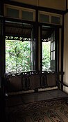 Part of the porch showing the glass transom, canopy, glass windows and antique furniture