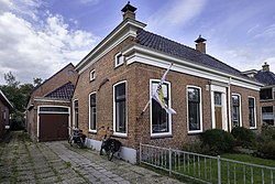 Woning met erachter het gebouw van de voormalige coöperatieve stoomzuivelfabriek Garmerwolde (1889-1919) aan de Dorpsweg 41, dat een industrieel monument vormt.