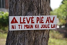 Panneau en créole de Guadeloupe signifiant : « Ralentissez, nos enfants jouent ici » et plus littéralement : « Lève ton pied (de l'accélérateur), il y a des enfants qui jouent là ».