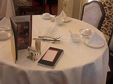 When a group of people sit at a table in for a dinner, several type of restaurants will charge an additional fee even for a guest who does not order any food; this charge is for the service of setting out the tablecloth, napkin, and cutlery. HK Central City Hall lower block Chinese restaurant table setting Oct-2012.jpg