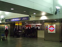 The interior of a building with people walking in various directions under a blue sign reading "HEATHROW TERMINALS 1, 2, 3 UNDERGROUND"