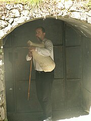 Joueur de kaba devant l'entrée de la grotte de Trigrad.