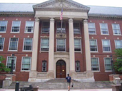 A photograph of the entrance to a building displaying three stories of windows, a four-column portico, and a sign reading "BOSTON LATIN SCHOOL".