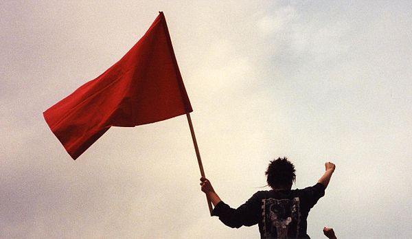 Left-wing protester wielding a red flag with a raised fist, both symbols of revolutionary socialism