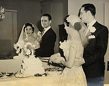 The bride and groom cut the wedding cake at an American wedding reception in 1955. MomDadwedding1955 photos.jpg