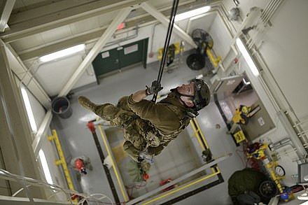 Pararescuemen from the 103d Rescue Squadron rappel from the top of a parachute drying facility to conduct confined space rescue training.