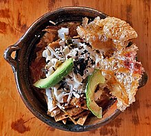A bowl of tortilla soup, garnished with cheese, avocado, and chicharron Sopa de tortilla con chicharron de real del monte.jpg