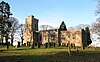 A stone church seen from a slight angle, with an embattled tower on the left, the nave in the centre, and the chancel on the right