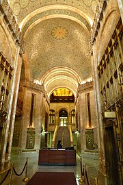 Photograph showing part of the lobby with an ornate ceiling and a staircase in the background