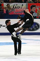 Male ice dancer in Besti squat while lifting his partner