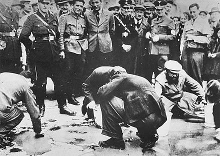 Des citoyens juifs sont forcés de s'agenouiller et de nettoyer le sol sous le regard de nazis et d'habitants viennois. Avril 1938. Collection USHMM.