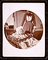 Baby in carriage, woman standing behind (3334088878).jpg