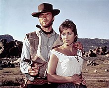 Live action movies (such as A Fistful of Dollars) use photography to depict settings and characters as they appear in life. In this example, Clint Eastwood and Marianne Koch appear in a real-world location Clint Eastwood and Marianne Koch in "A Fistful of Dollars" (1964).jpg