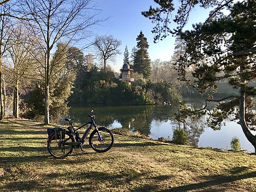 Moustache electric bike with the kiosk of the emperor in bois de Boulogne, Paris