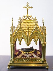 Reliquaire en or avec un coussin au milieu sur lequel est posée une natte marron.