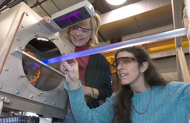 Extruded plastic scintillator material fluorescing under a UV inspection lamp at Fermilab for the MINERνA project