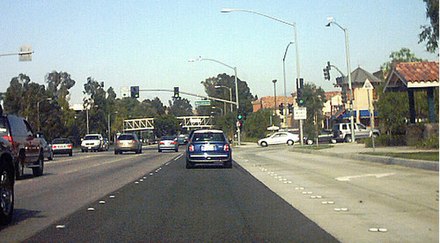 A stretch of Valencia Boulevard in July 2004, near the Westfield Valencia Town Center. The bridge in the distance carries a paseo (a type of dedicated pedestrian pathway) over the roadway.