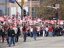 Um grande grupo de pessoas em frente a um prédio, fazendo piquete com placas dizendo "Writers Guild of America on Strike".