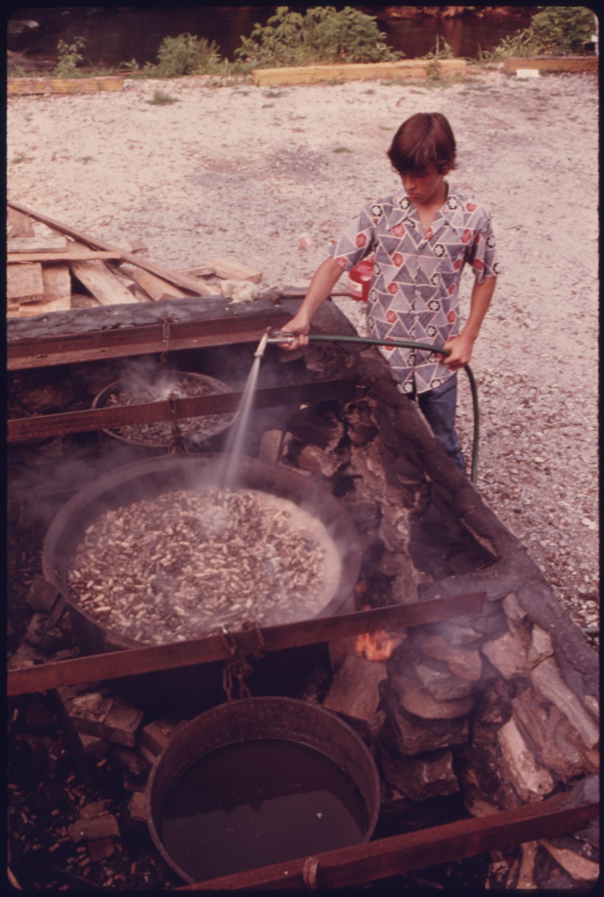 YOUNGSTER SPRAYS WATER ON BOILING PEANUTS IN HELEN, GEORGIA NEAR ROBERTSTOWN. HELEN WAS A TYPICAL SMALL MOUNTAIN... - NARA - 557700.tif