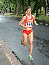 Photographie : une femme en tenue de sport avec un dossard court sur une route