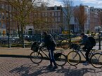 Amsterdam 2023, photo of young boys from school are climbing an old brick bridge Korrelbrug with their bikes over the canal Boerenwetering in sunlight of early Springfree download photo by Fons Heijnbroek, street photography in The Netherlands, CCO