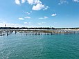 Des parcs à huîtres devant la plage du Mimbeau au Cap-Ferret, avec le phare et le château d’eau de la presqu’île en arrière-plan.