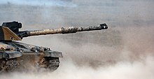 Challenger 2 after firing a high-explosive shell during a firepower demonstration. The power of tank guns can cause the ground to shake and dust to rise. Challenger 2 Firing High Explosive Shell MOD 45150011.jpg