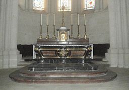 Photographie en couleurs d'un tabernacle doré surmonté d'une croix et posé sur un autel.