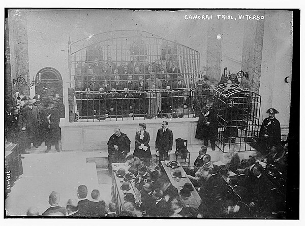 The Cuocolo Trial. Most of the defendants are in the large cage. The three in front are (from left to right) the priest Ciro Vitozzi, Maria Stendardo,