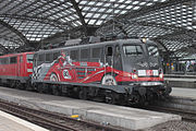 29. KWDie Einheitselektrolokomotive DB 115 509-2 auf dem Kölner Hauptbahnhof mit der Sonderlackierung 80 Jahre DB AutoZug.