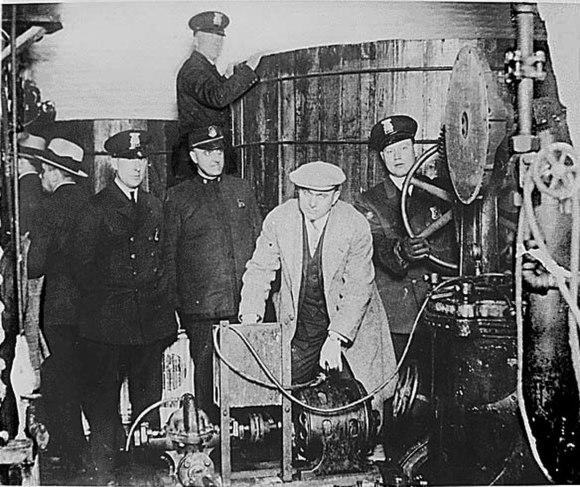 Detroit policemen inspect the equipment used in a clandestine brewery during the Prohibition era.