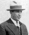 Sort og hvidt foto af en mand iført en dragt og en hat