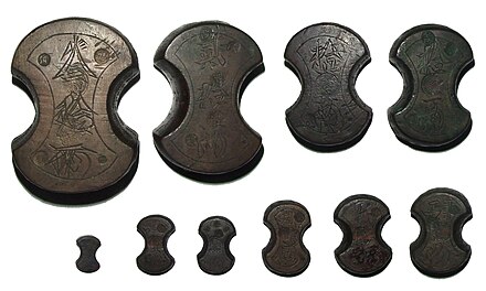 A set of ten traditional Japanese fundō weights, used by money changers to weigh coinage.  Top row from left are 30 ryō (1124.66 g), 20 ryō (749.07 g) and 10 ryō (374.62 g, twice), bottom row from left are 3 momme (11.19 g), 1 ryō (37.47 g, twice), 2 ryō (74.89 g), 3 ryō (112.42 g) and 4 ryō (149.77 g).  All metric weights actual, not rounded.