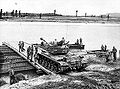 An American M46 tank moves onto a British ferry at a river in Korea, 1951.