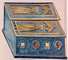 Kék márvány kettős síremlék, tetején két réz nőalak hosszú ruhában, hármas boltív alatt. Oldalt címerek.